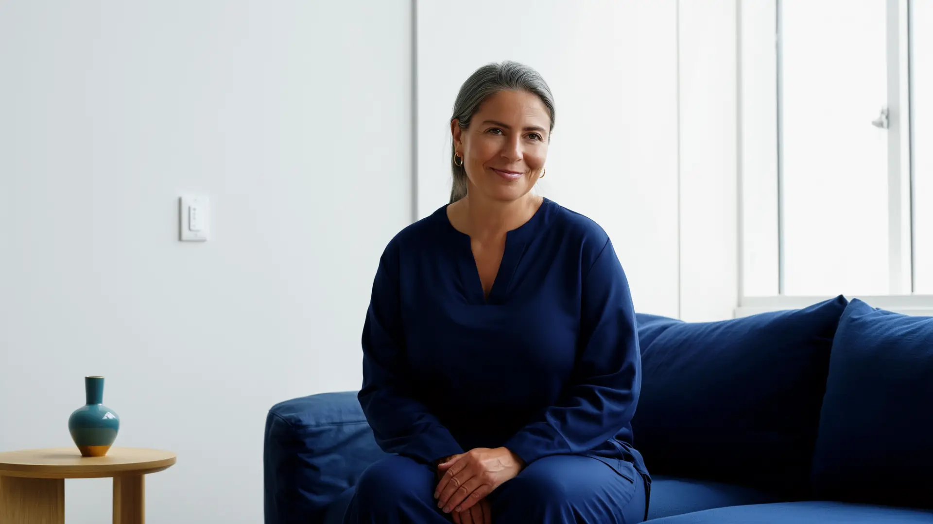 A woman relaxing on a navy sofa in a bright living room