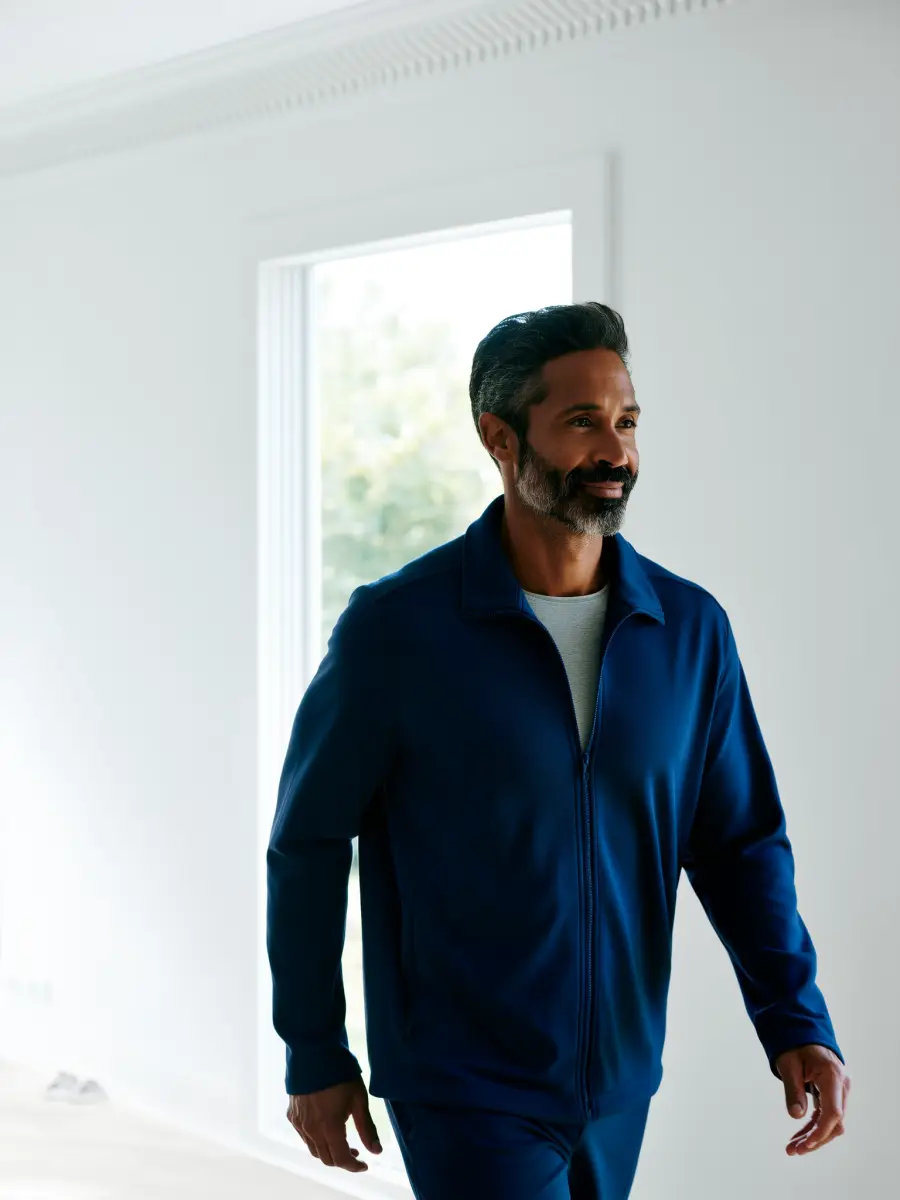 A smiling man walking through a bright room